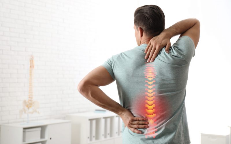 Man suffering from pain in back at clinic. Visiting orthopedist