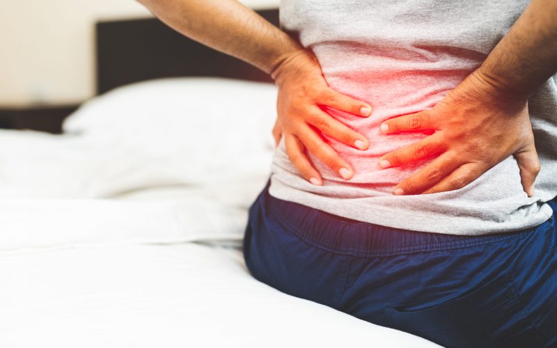 woman suffering from back pain on the bedroom.